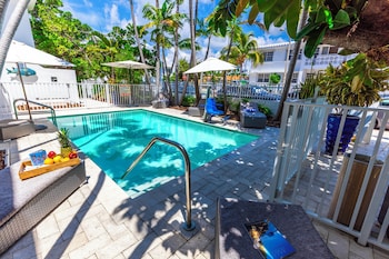 A modern hotel room with two beds, a TV, a minibar, and a view of the beach. at Seaside All Suites Hotel
