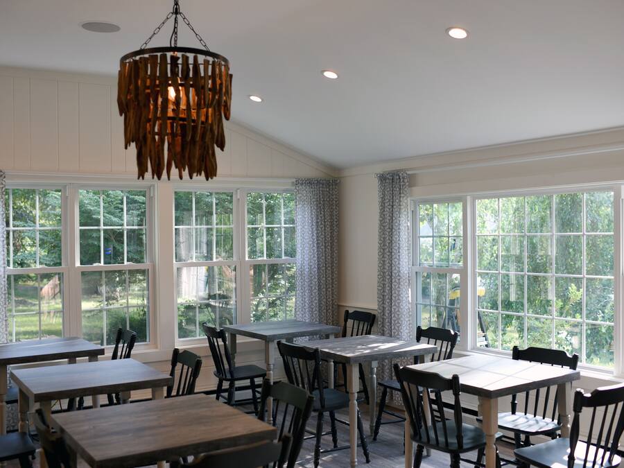 A dining area with large windows, wooden tables, and chairs.