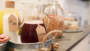Una bandeja con un jarro de jugo de arándano, una botella de leche y frascos de granola.