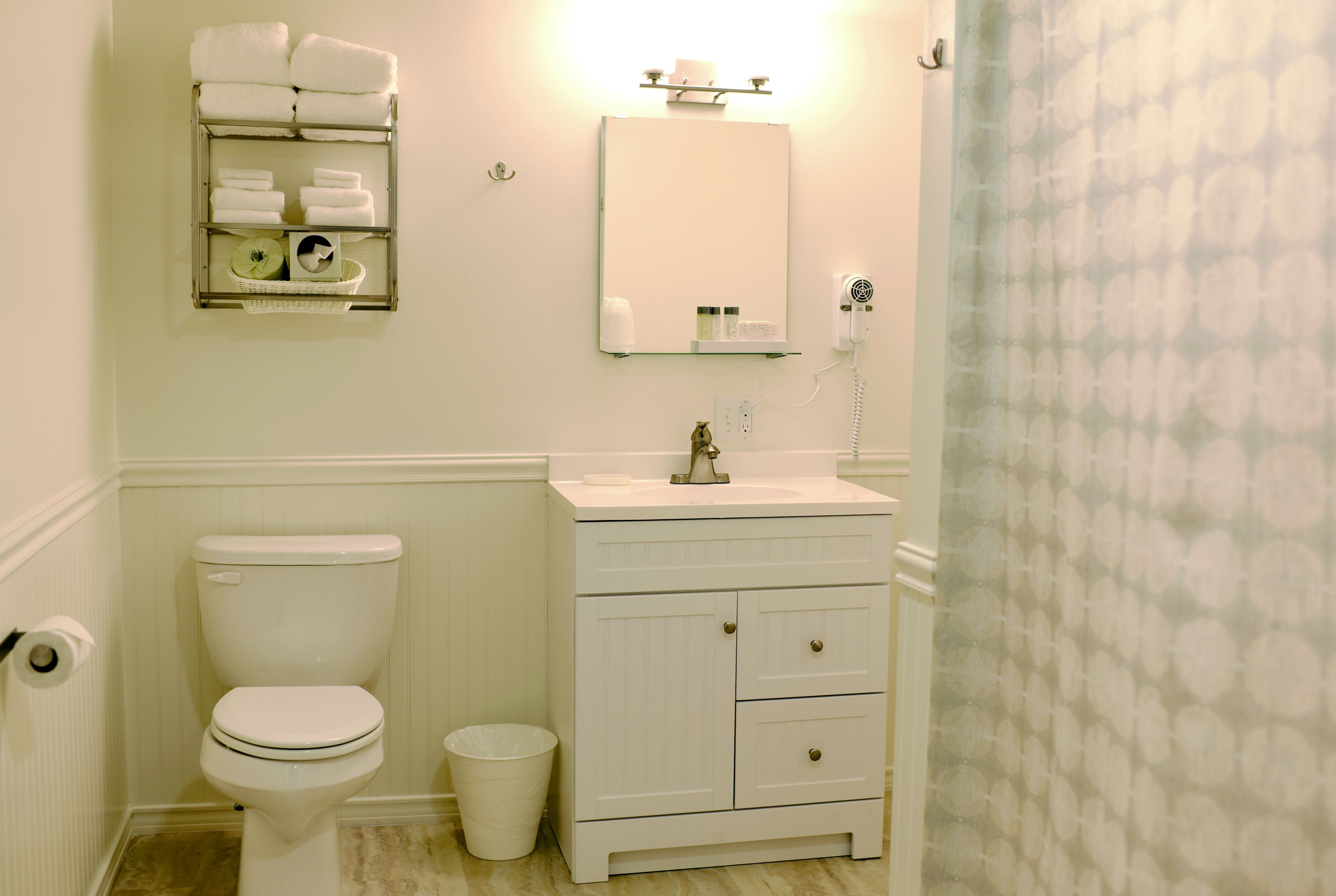 Une salle de bain équipée de toilettes, d’un lavabo et d’un porte-serviettes avec des serviettes pliées.