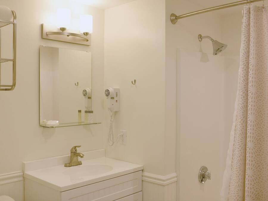 A bathroom with a white sink, mirror, and a shower with a glass door.