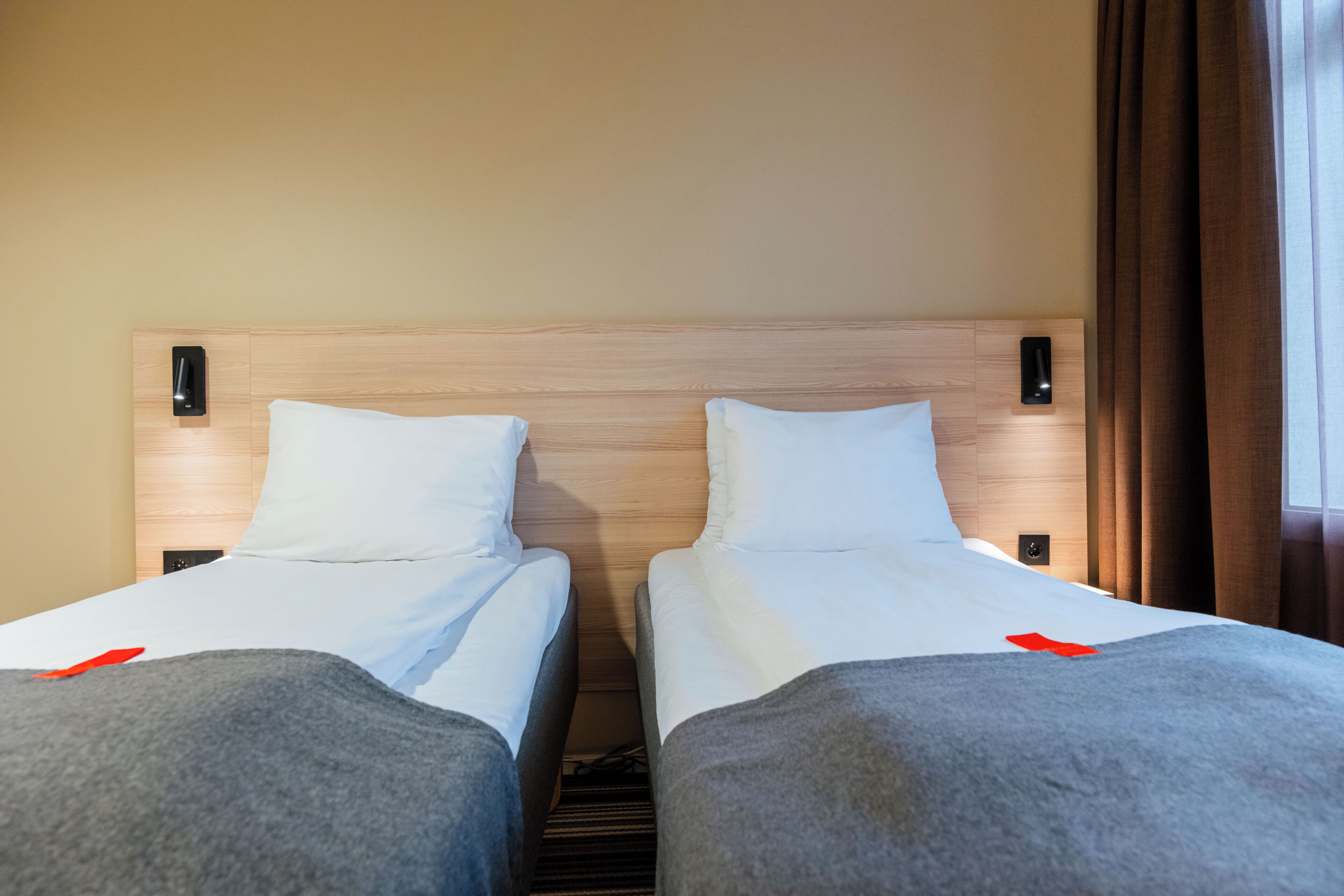 Een hotelkamer met twee eenpersoonsbedden, houten hoofdborden en bedlampen.