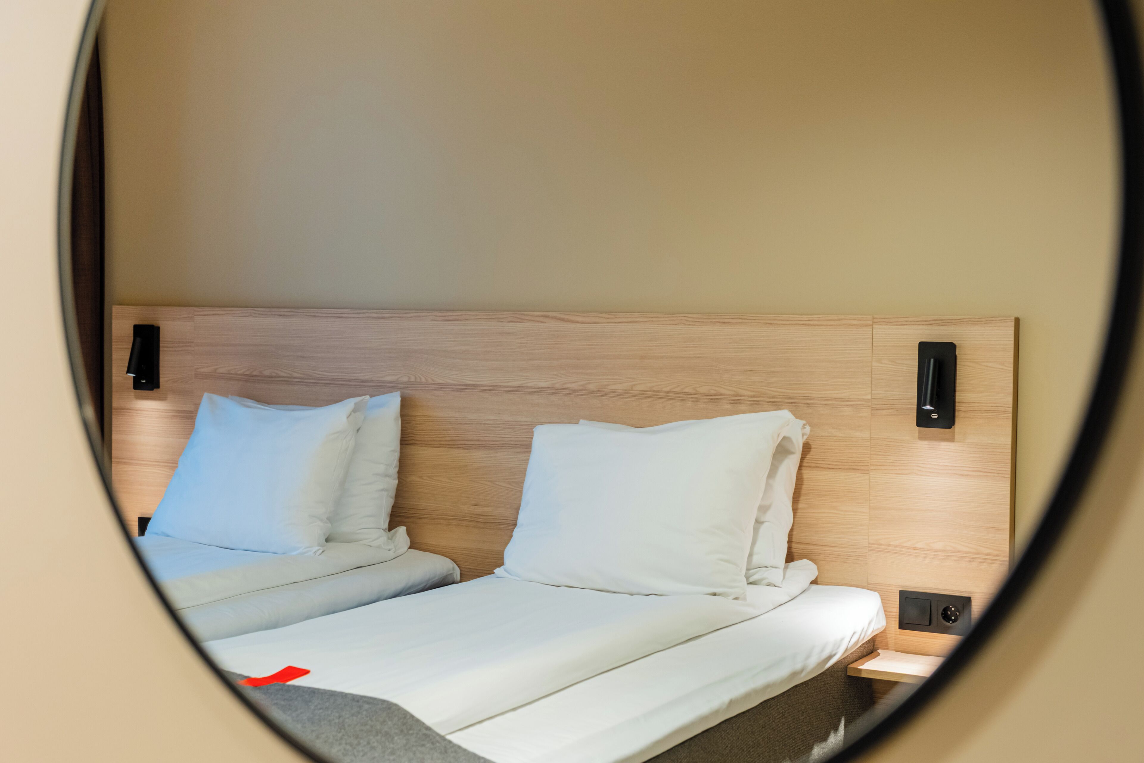 A bed with a wooden headboard, two pillows, and a bedside table with a lamp.