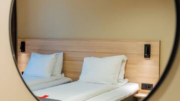 A bed with a wooden headboard, two pillows, and a bedside table with a lamp.