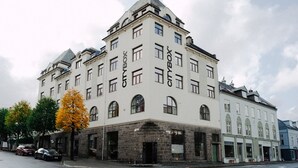 En bygning med flere etager, hvid facade og buede vinduer.