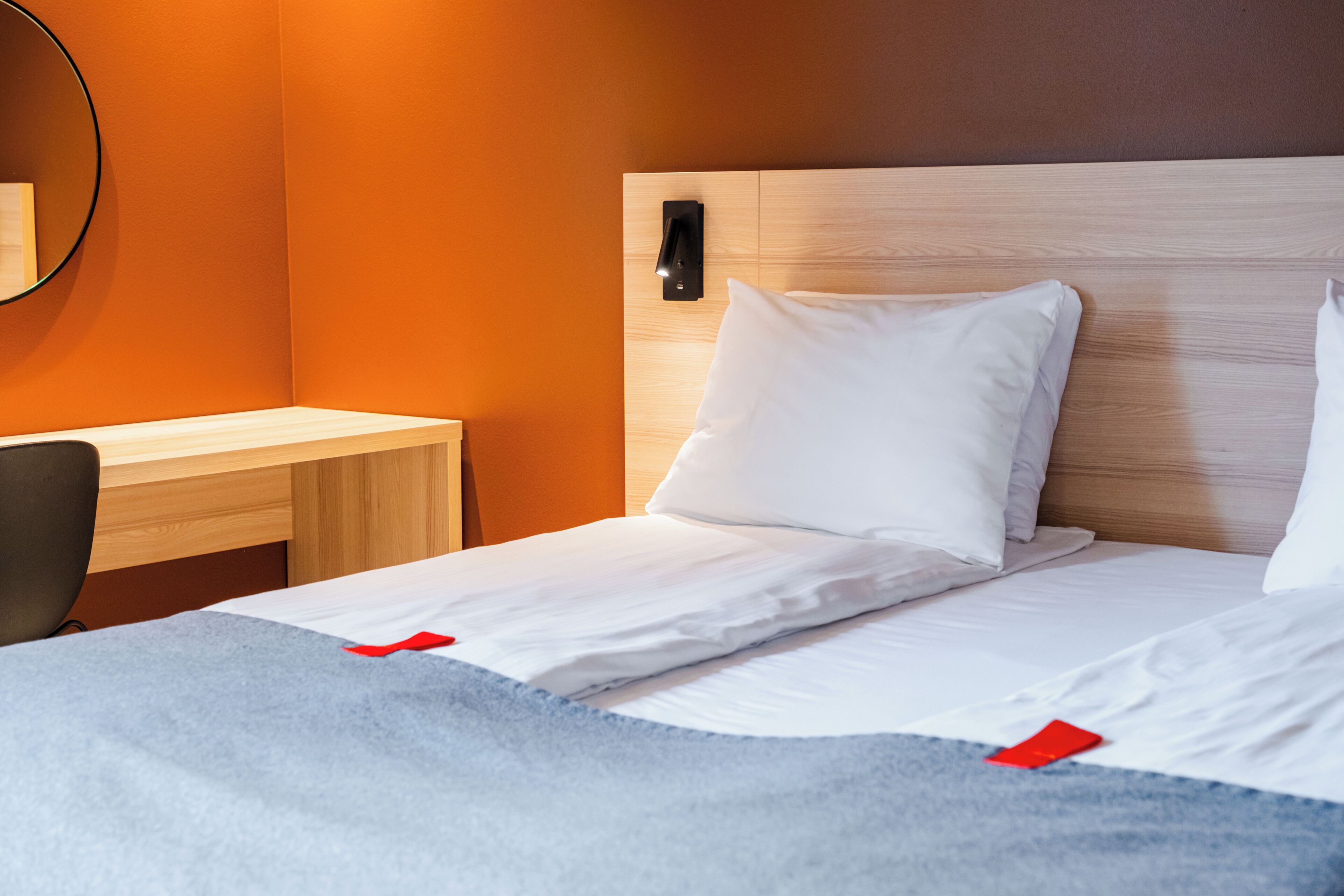 A hotel room with a bed, a desk, and a mirror.