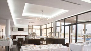 A modern restaurant with white tablecloths, brown upholstered chairs, and large windows offering a view of the outdoors.