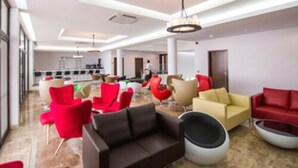 A spacious lobby with modern seating arrangements and a visible kitchen area in the background.