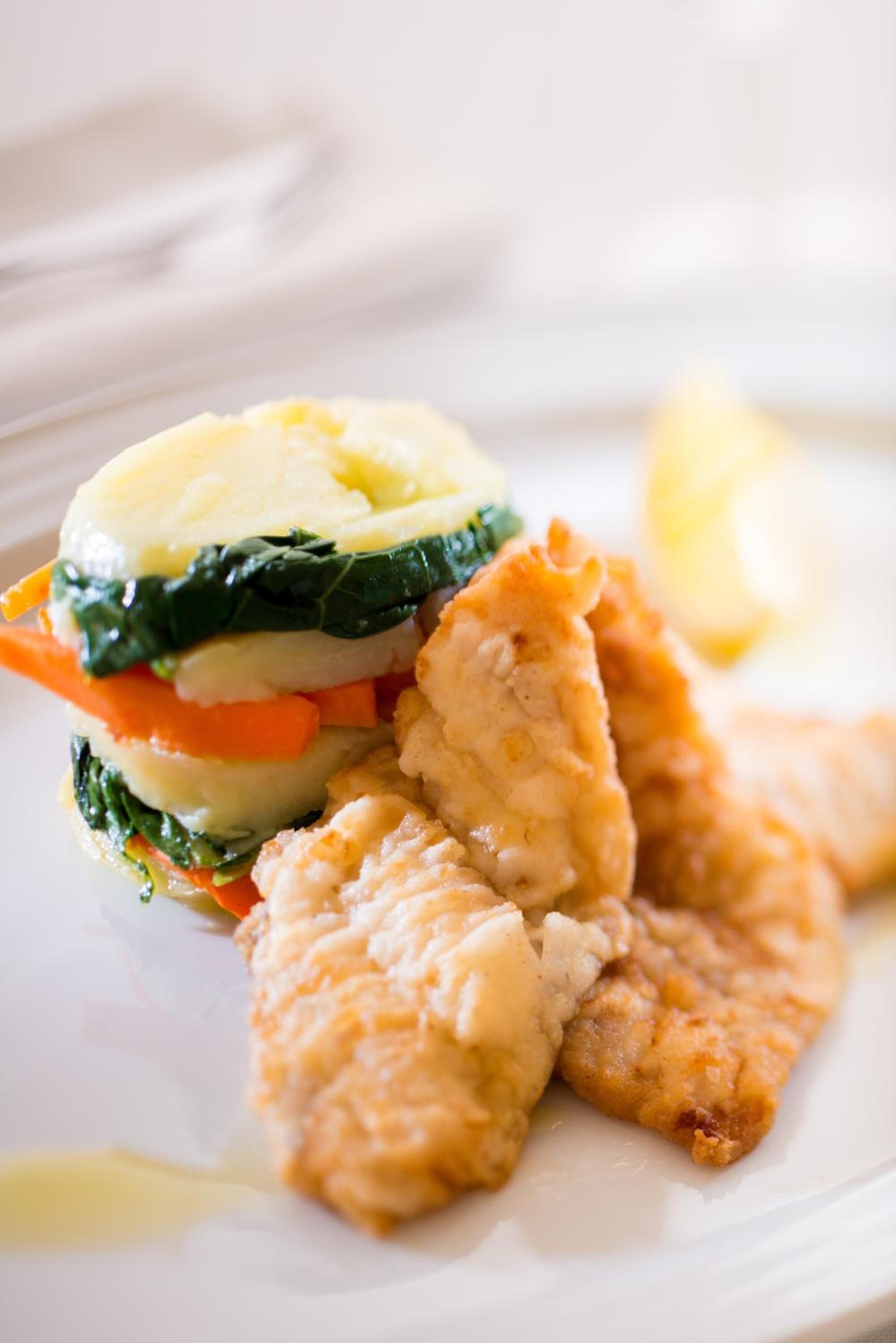Une assiette comprenant un filet de poisson, de la purée de pommes de terre et un mélange de légumes.