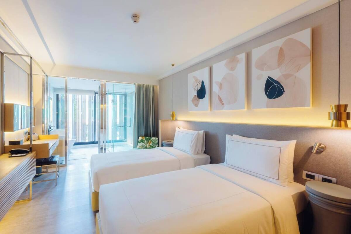 Ein modernes Hotelzimmer mit zwei Betten, einem Schreibtisch und einem großen Fenster.