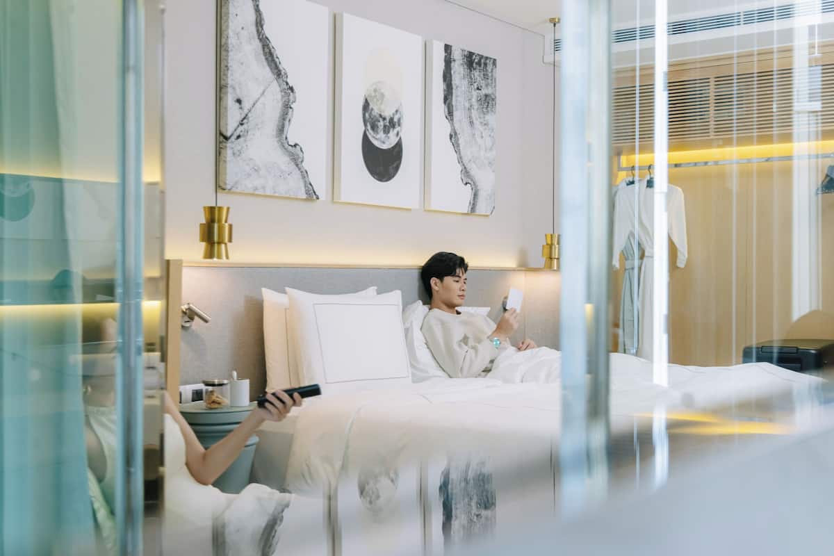 Ein modernes Hotelzimmer mit Bett, Nachttisch und einem Kunstwerk an der Wand.