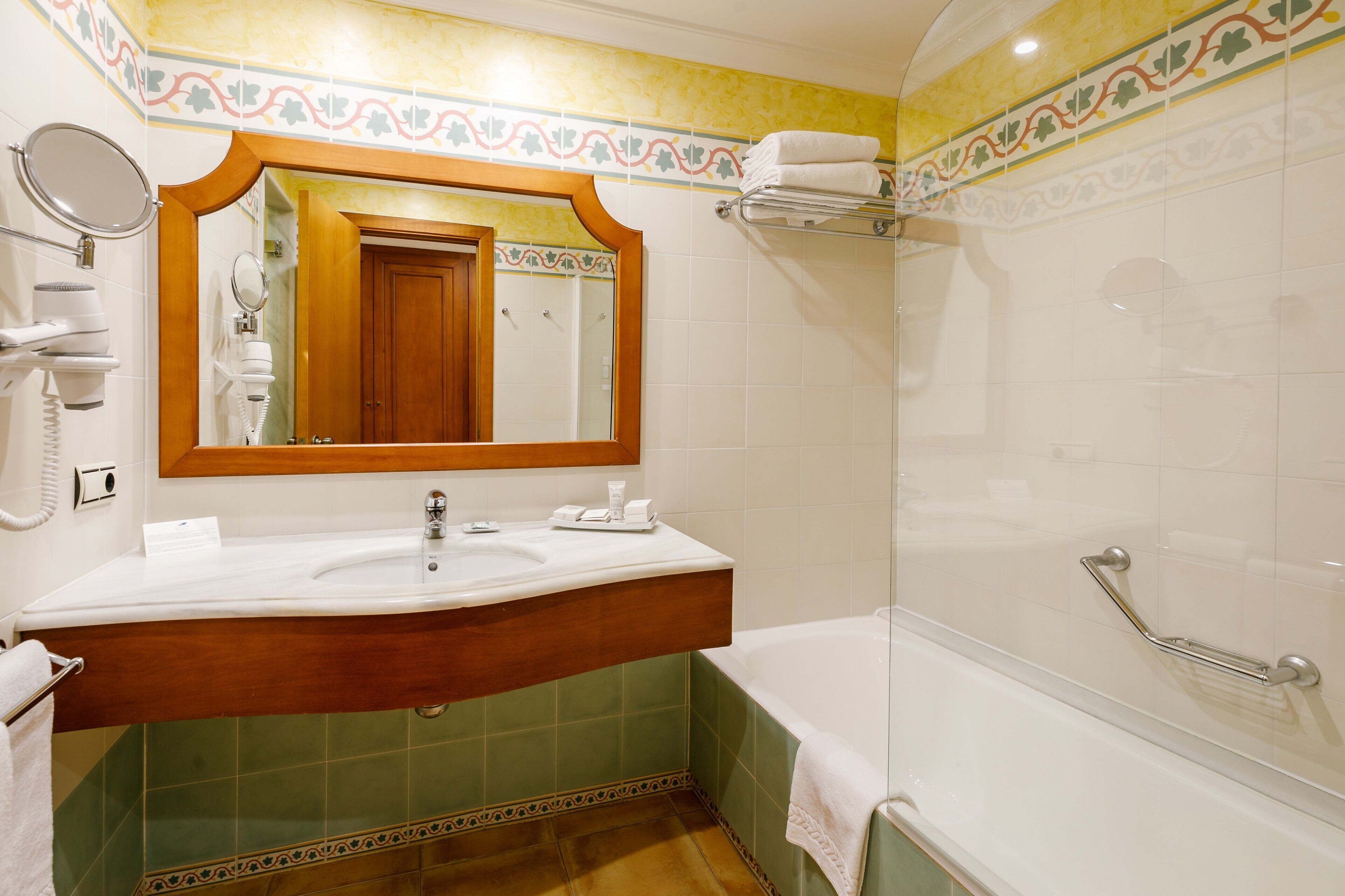 Een badkamer met wastafel, spiegel en bad.