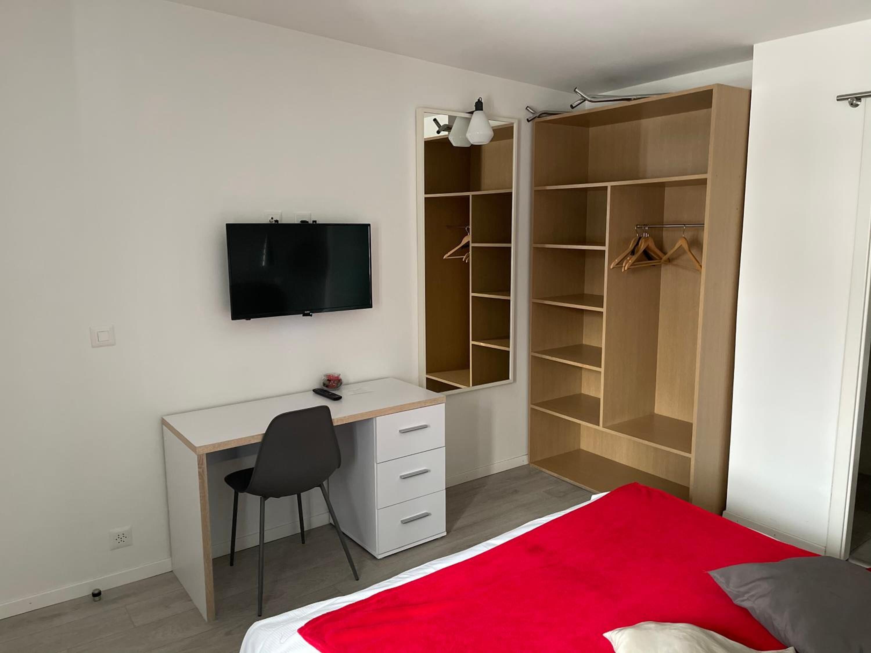 A bedroom with a bed, a desk, a chair, a TV, and a wardrobe.