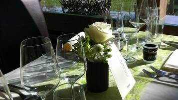 Una mesa preparada para una comida, con copas de vino, un jarrón con flores y un menú.