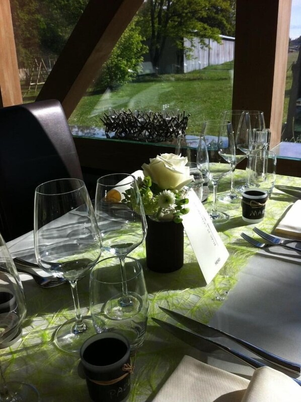 Una mesa preparada para una comida, con copas de vino, un jarrón con flores y un menú.