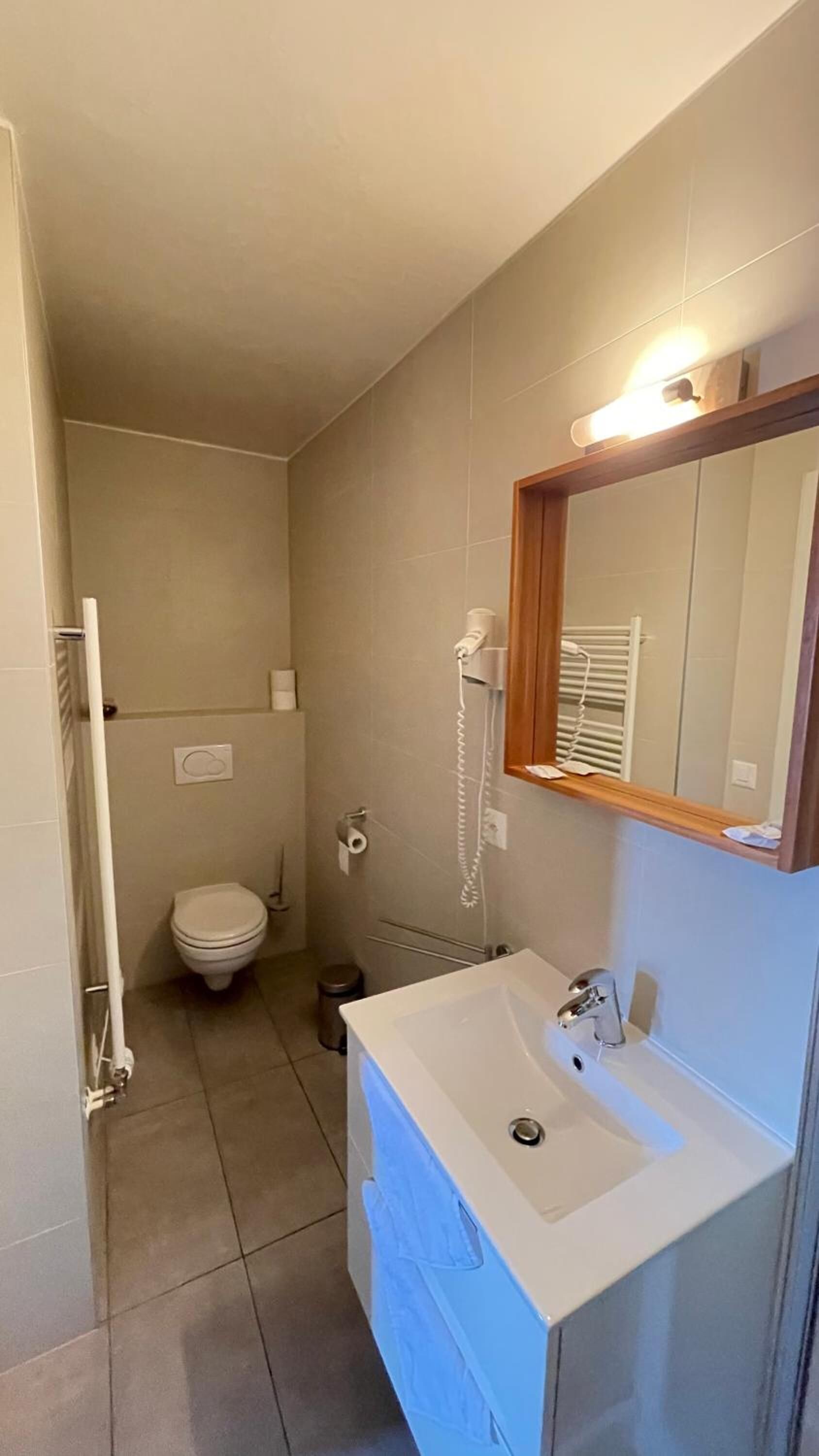 Ein kleines Badezimmer mit Waschbecken, Spiegel und Toilette.