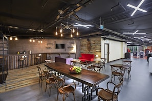 A spacious dining area with a long wooden table, multiple chairs, and a fruit bowl centerpiece.