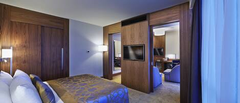 A hotel room with a bed, a TV, and a bathroom visible through an open door.