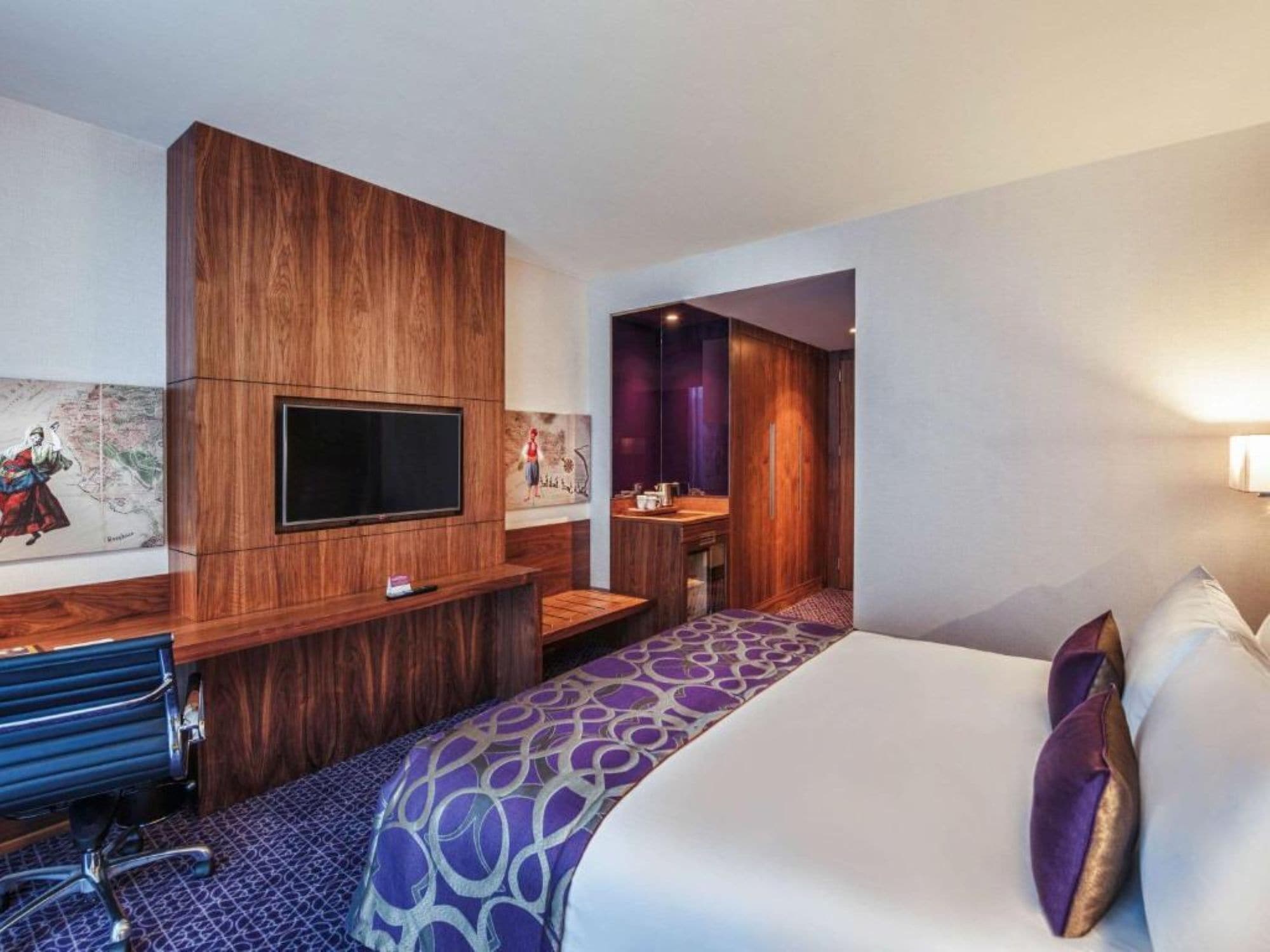 Une chambre d’hôtel dotée d’un grand lit, d’un bureau avec un téléviseur à écran plat, d’une armoire en bois et d’une salle de bain avec un miroir et un lavabo.