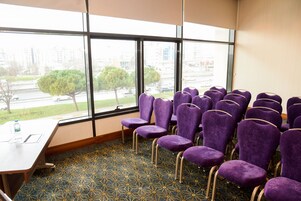 Una sala de conferencias con sillas moradas, una mesa de madera y una alfombra estampada.