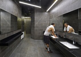 A modern bathroom with dark tiles, a large mirror, and a sink.