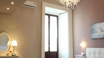 Une chambre à coucher avec un grand lit, un lustre, une table de chevet, un miroir et un tableau accroché au mur.