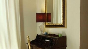 A room with a wooden desk, a chair, a mirror, and a lamp.