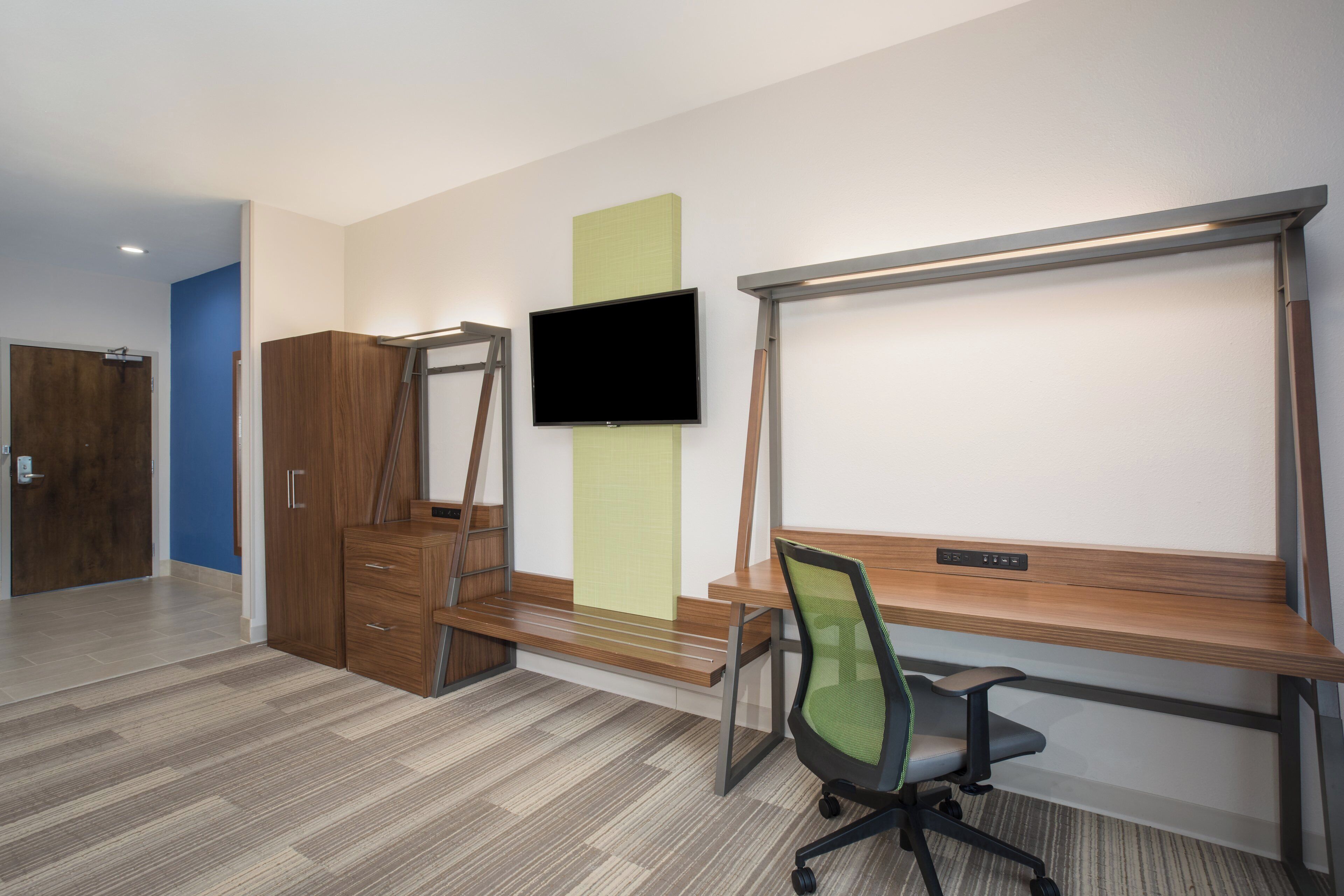 Un espacio de oficina moderno con escritorio, silla, televisor, armario y una puerta.