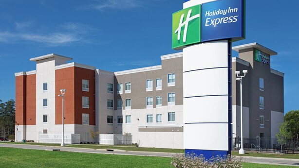 A Holiday Inn Express hotel with a modern design, featuring a mix of brick and stucco exteriors, multiple windows, and a prominent signage.