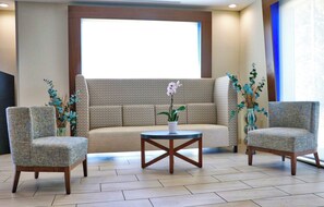 A seating area with a sofa and two armchairs, a small round table, and decorative plants.