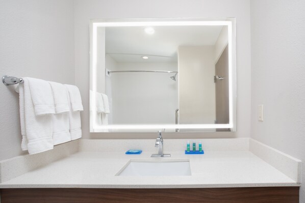 Un baño con lavamanos blanco, un espejo y un toallero.