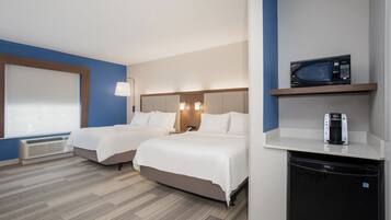 Habitación de hotel con dos camas, microondas, cafetera y refrigerador pequeño.