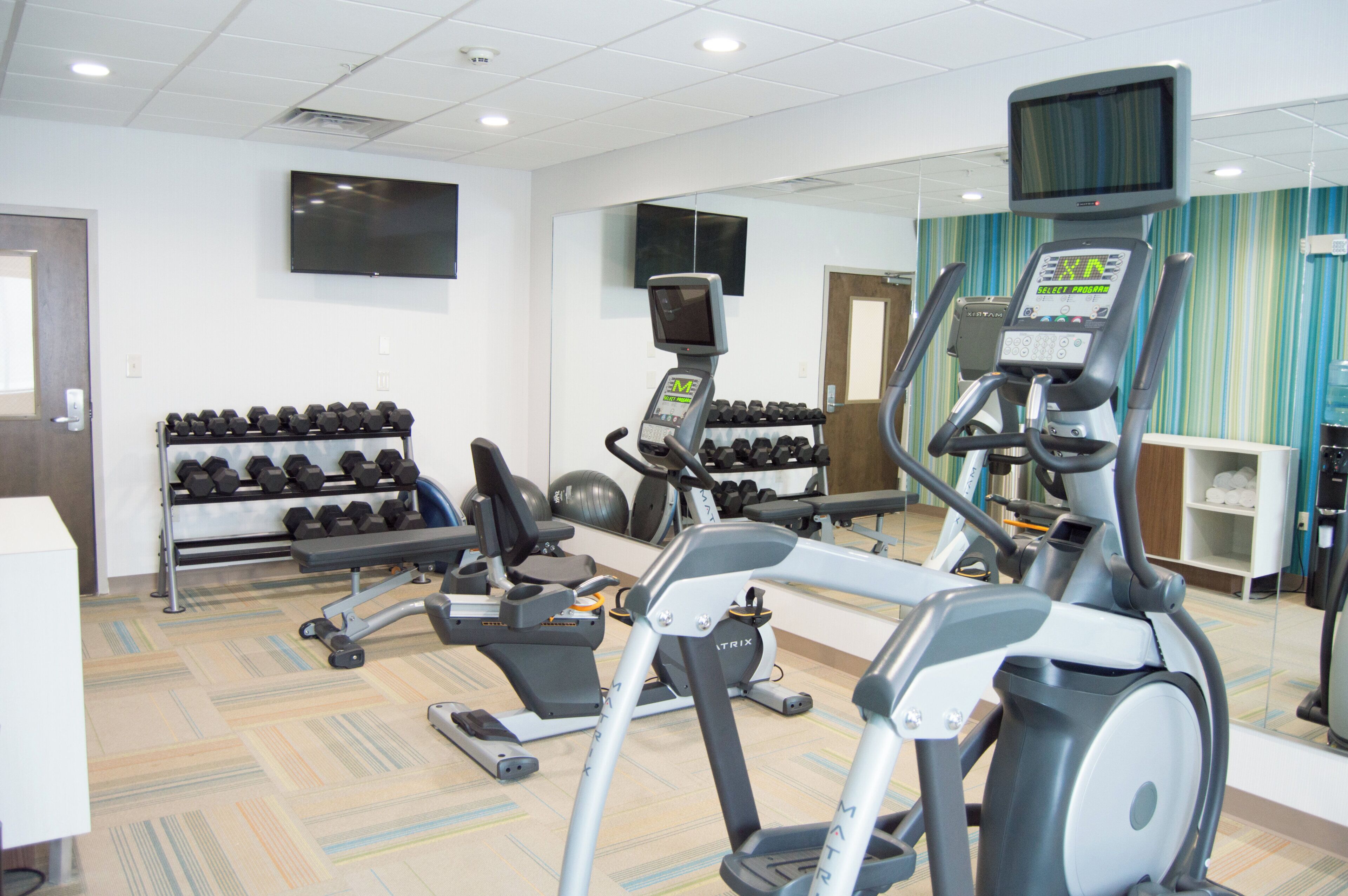 A gym with treadmills, dumbbells, and exercise balls.