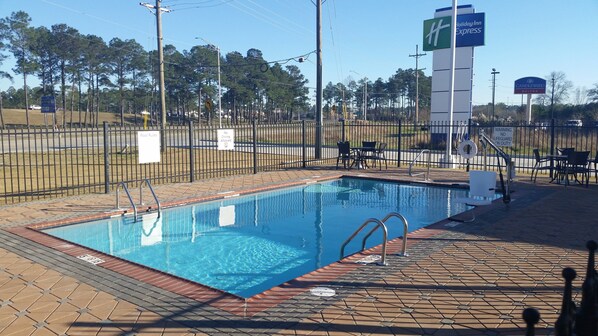 A swimming pool with a fenced area, pool rules sign, and a lifeguard duty sign.