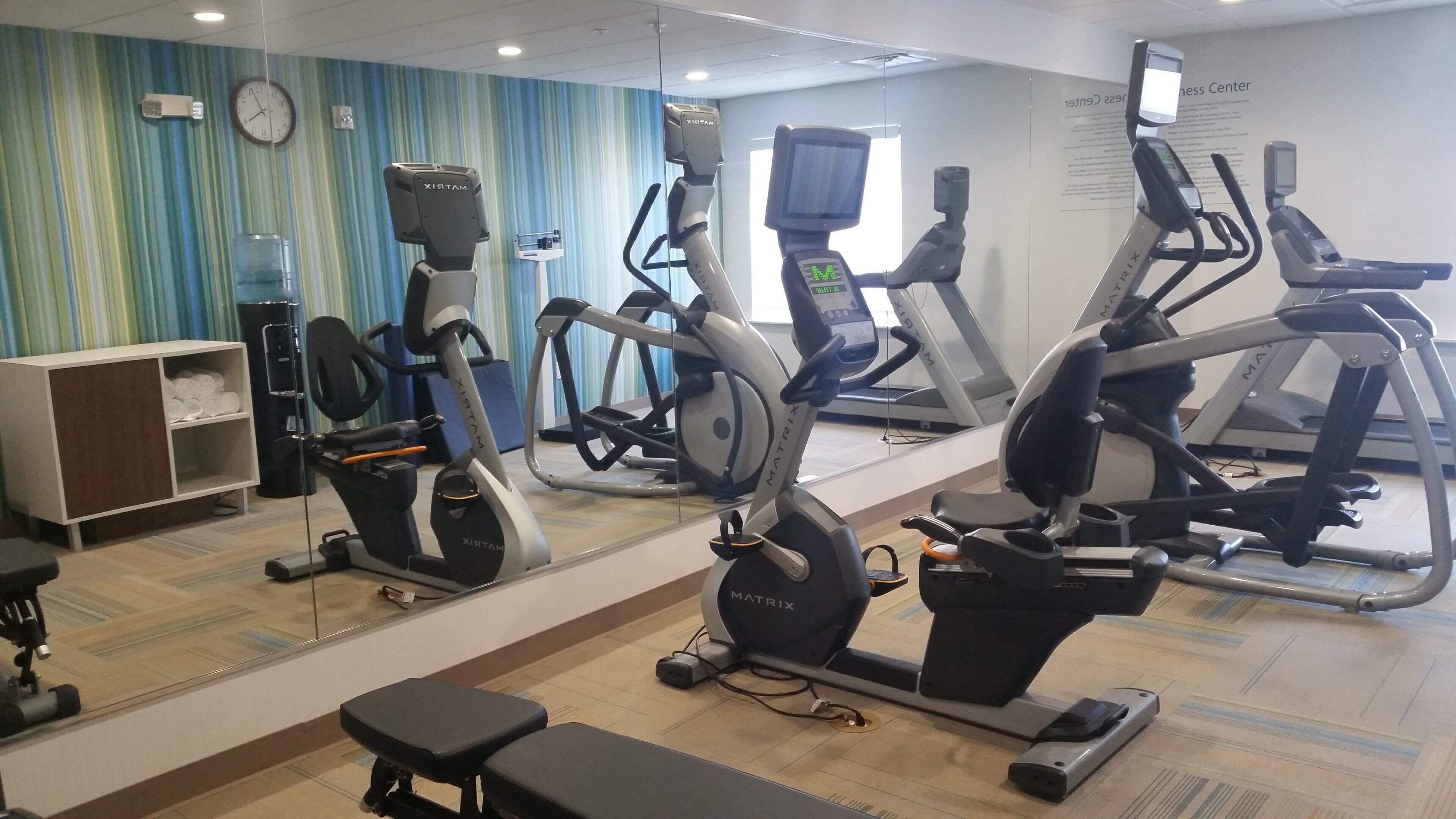 A gym with various exercise equipment including treadmills, stationary bikes, and an elliptical.