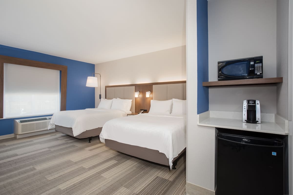 Hotellihuone, jossa on kaksi sänkyä, mikroaaltouuni, kahvinkeitin ja pieni jääkaappi.