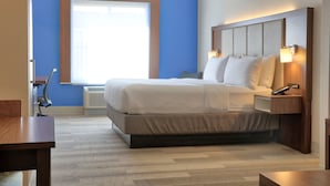 Una habitación de hotel moderna con una cama grande, lámparas de noche y una ventana con persianas.