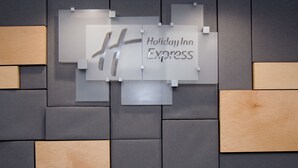 Una pared con el letrero de Holiday Inn Express y un diseño geométrico de paneles grises y de madera.