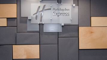 Una pared con el letrero de Holiday Inn Express y un diseño geométrico de paneles grises y de madera.