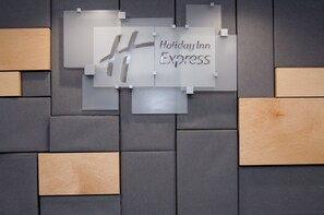 Un mur orné d’une enseigne Holiday Inn Express et d’un motif géométrique composé de panneaux gris et en bois.