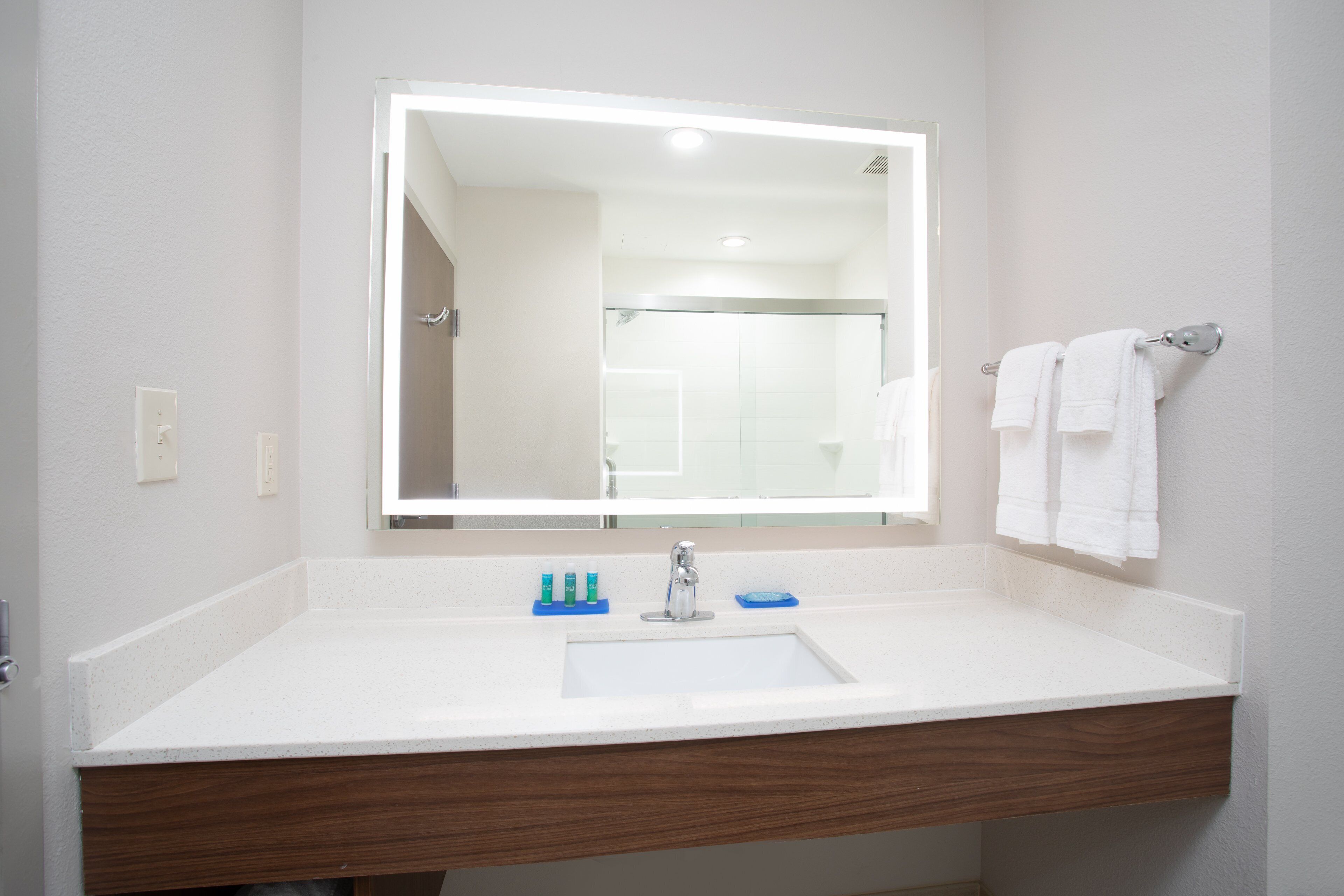 Un bagno con un lavandino bianco, uno specchio e un porta asciugamani.
