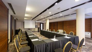 A conference room with a long table, chairs, and a projector screen.