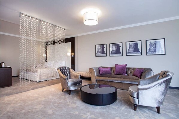 A modern living room with a sofa, two armchairs, a coffee table, and a decorative hanging light fixture.