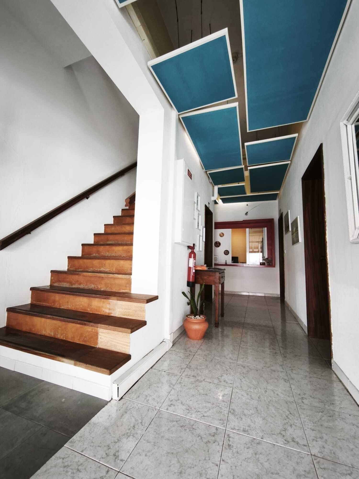 Una escalera conduce a un rellano con piso de baldosas y una planta en maceta.