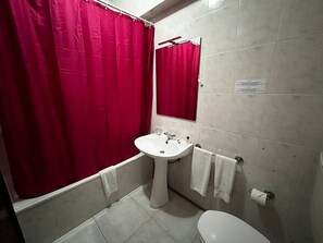 Une salle de bain avec un lavabo blanc, des toilettes et un rideau de douche rouge.