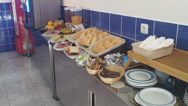 A buffet setup with various food items and utensils. - Hotel J.S.F. (Horta)