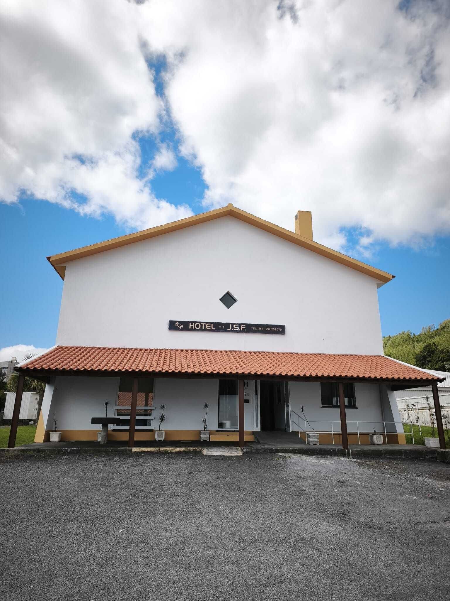 A two-story building with a sign indicating it is a hotel. There is a small entrance with steps leading up to the door.