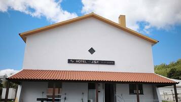 A two-story building with a sign indicating it is a hotel. There is a small entrance with steps leading up to the door.