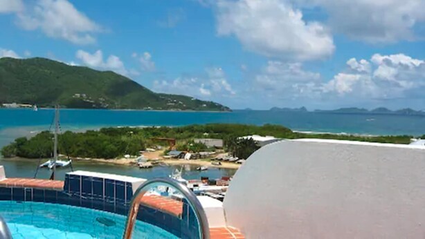 A swimming pool with a view of a coastal area, including a body of water and distant mountains. - Fort Burt Hotel (Road Town)