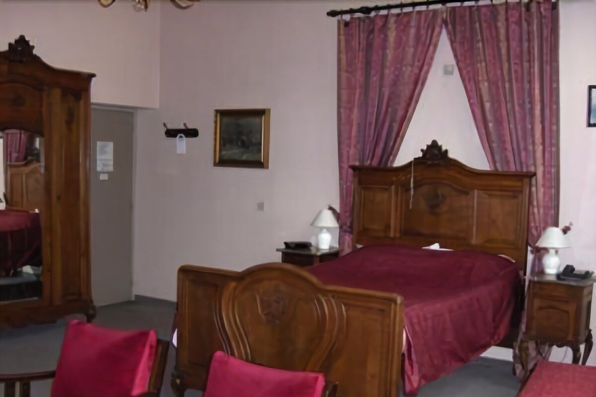 A bedroom with a wooden bed, two bedside tables with lamps, a chair, and a wardrobe.